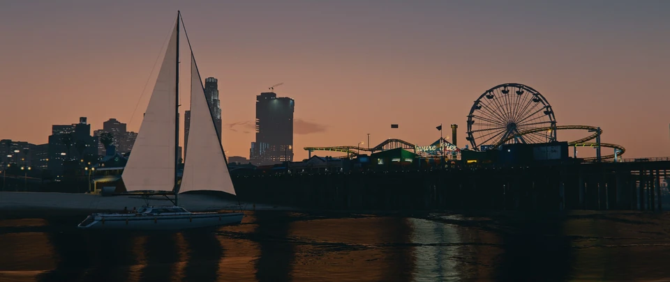 A sailboat on the water with a city skyline and ferris wheel at sunset